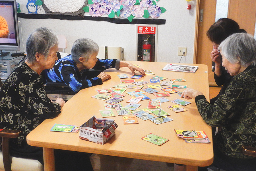 グループホームおきだての屋内テーブルでかるたを楽しむ入居者