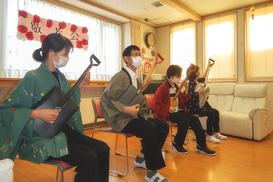 グループホームおきだての敬老会でスコップ三味線を披露している方々