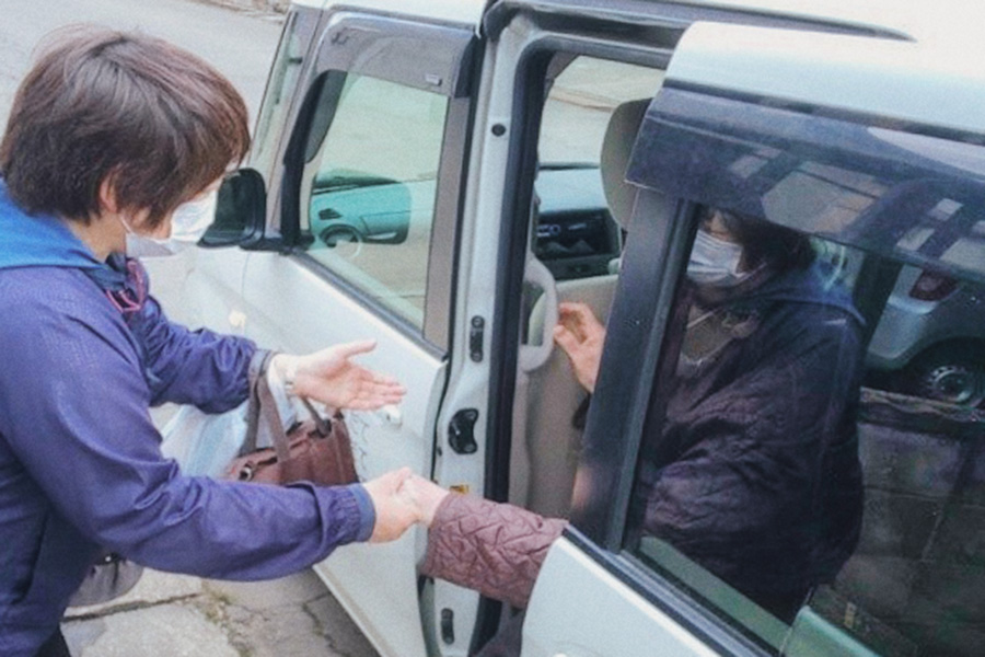 ヘルパーステーションおきだての送迎車から降りてくる利用者